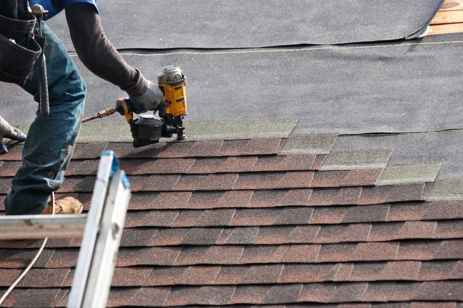 Worker installing shingles on roof 