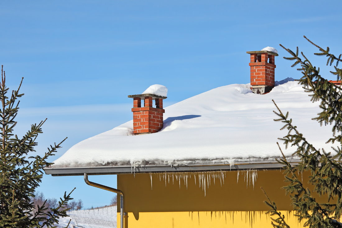 Snow on roof of a yellow house on a sunny day