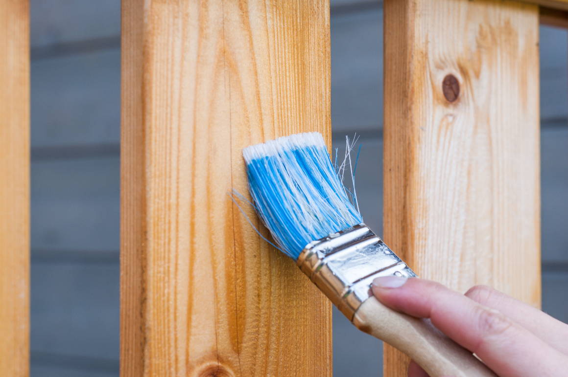 Person Applying Varnish To A Deck With Paint Brush