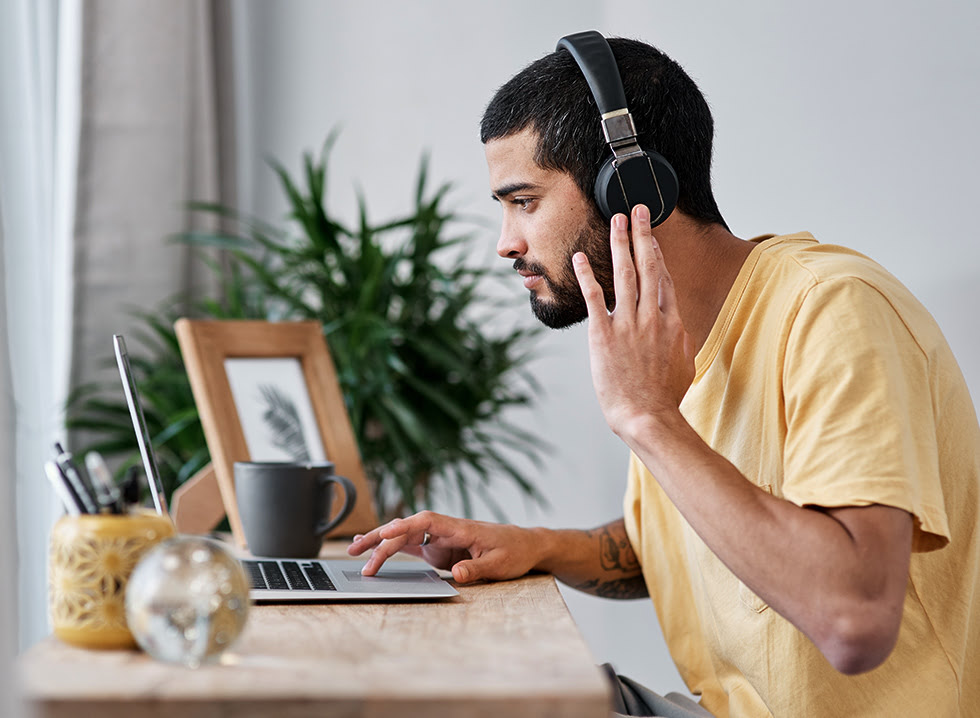 Man with noise-canceling headphones using a laptop