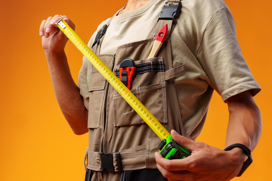 Roofer holding tape measure with other tools for measuring gutter size