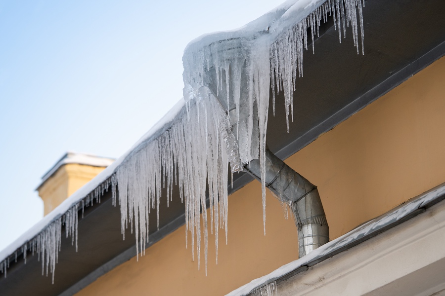 Ice dam forming around blocked downspout of home in winter
