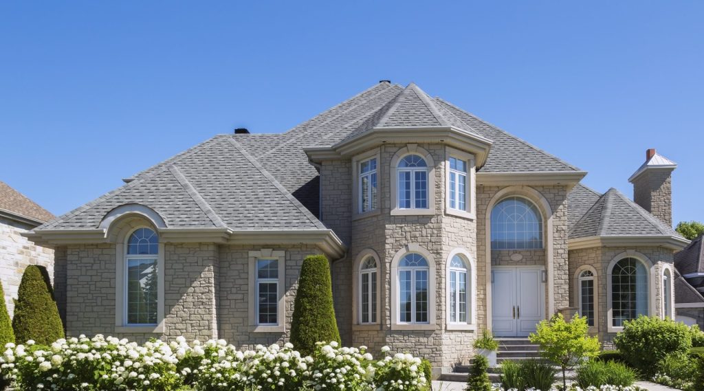 A mansion with a natural stone exterior, arched windows, and peaked roofs.