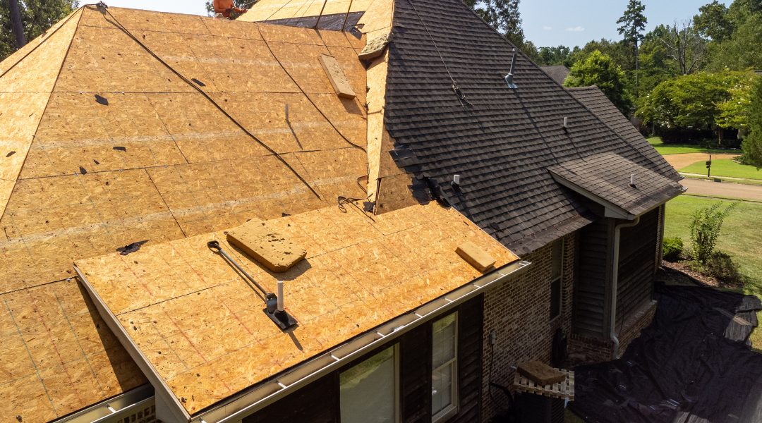 Big5 time to replace hero A house with its roof being replaced in springtime, with the sun shining. Half of the roof has the shingles already installed; the other half is just wood decking.